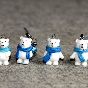 以下が含まれることがあります： 青いスカーフをつけた白いホッキョクグマのチャームが4つ。チャームはプラスチック製で、キーホルダーやその他のアイテムに取り付けるための銀色のループが付いています。