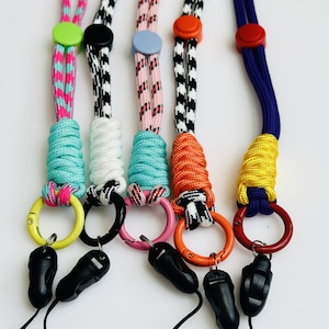 May include: Five colorful lanyard keychains with different patterns and colors. Each keychain has a metal ring and a plastic clip. The keychains are made of braided rope.