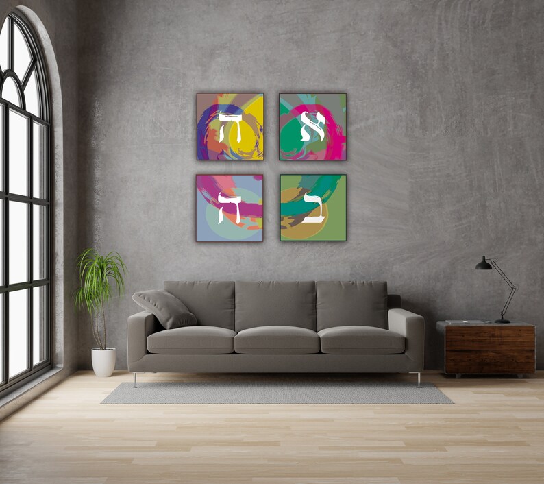 May include: Four square abstract art prints with Hebrew letters in white on a gray background. The prints are arranged in a grid pattern on a gray wall above a gray couch.