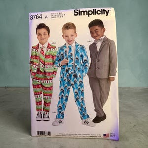 May include: Simplicity sewing pattern 8764 for children's suits in sizes 3-8. The envelope displays three variations: a red and green holiday print suit, a blue shark print suit, and a solid grey suit, each including a matching tie and jacket.