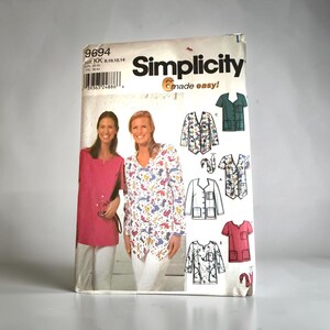May include: A Simplicity 9694 sewing pattern envelope for scrub tops. The cover features two people wearing solid pink and patterned scrub tops with white pants. Illustrations show five variations of the top with pockets and different sleeve lengths.