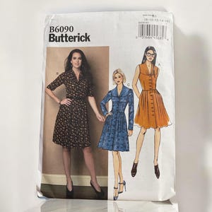 May include: A sewing pattern for three dresses. The pattern is from Butterick and the pattern number is B6090. The dresses are in different colours and styles. One dress is brown with a floral print, one is blue with a pleated skirt, and one is orange with a pleated skirt.