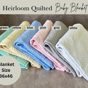 K&ouml;nnte beinhalten: Heirloom gesteppte Babydecken in verschiedenen Farben: Gr&uuml;n, Gelb, Blau, Rosa, Grau und Wei&szlig;. Jede Decke misst ca. 91x117 cm und weist ein detailliertes Steppmuster auf. Die Decken sind ordentlich gestapelt und zeigen ihre weiche Textur.