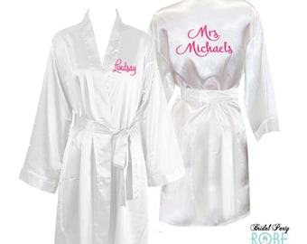 May include: Two white satin robes with pink embroidery. One robe says "Mrs. Michaels" and the other says "Lindsay".