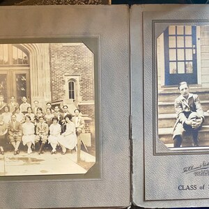May include: Vintage photo album open to two pages. One page features a group photo of a class in front of a building. The other page has a photo of a person sitting on steps. The album page is gray with a textured surface. The text "CLASS of 1925" is visible.