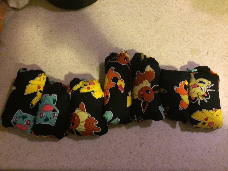 May include: A set of seven black cloth diapers with colorful Pokemon characters printed on them. The characters include Pikachu, Bulbasaur, Charmander, Squirtle, and Eevee.