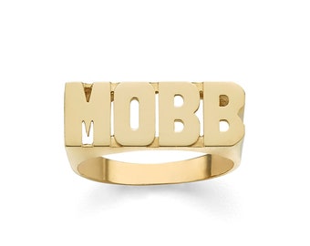 May include: A gold ring with the word "MOBB" spelled out in block letters.