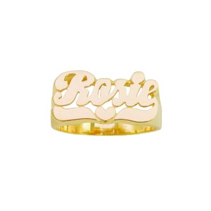 May include: Gold ring with the name "Rosie" spelled out in cursive letters with a small heart in the center.