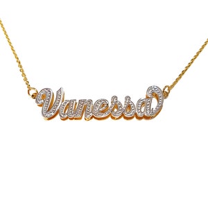 May include: A gold chain necklace with a diamond-encrusted pendant that spells out the name "Vanessa" in a cursive font.