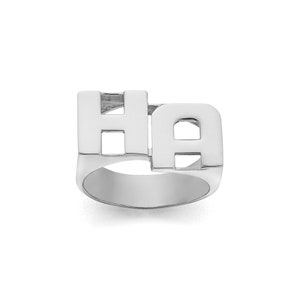 Peut inclure: Une bague en argent avec les lettres "HA" en police épaisse et carrée.