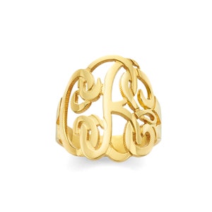 May include: A gold-toned ring with a monogram design. The ring features a large, open-style letter "F" with intricate swirls and curves.