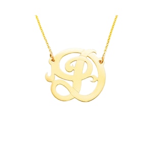 May include: A gold necklace with a pendant featuring a cursive letter 'P' in a circle.