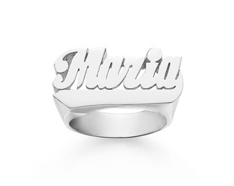 Könnte beinhalten: Ein silberner Ring mit dem Namen "Marcia" in einer fetten, kursiv geschriebenen Schrift.