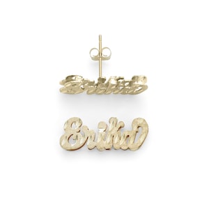 May include: Gold earrings with the name "Erika" spelled out in a cursive font. The earrings are made of 10k gold and have a diamond-cut finish.