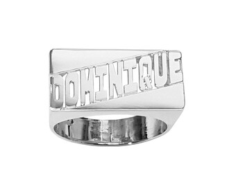 Könnte beinhalten: Ein silberner Ring mit der Gravur "DOMINIQUE" auf der Oberseite. Der Ring hat eine rechteckige Form.