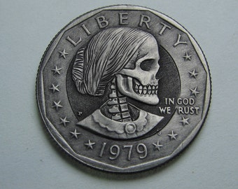 May include: A silver US dollar coin with a skull and crossbones design. The coin features the words "Liberty" and "In God We Trust" and the year "1979".