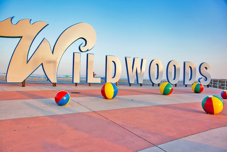 May include: A large silver sign spelling "WILDWOODS" with beach balls in front of it.