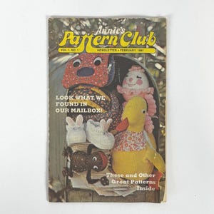 Può includere: Un'antica newsletter "Annie's Pattern Club" del febbraio 1980, con una copertina colorata. La copertina mostra vari oggetti fatti a mano, tra cui un oggetto a forma di cane, un'anatra e scarpine per bambini. Il testo sulla copertina recita "Look What We Found in Our Mailbox!"