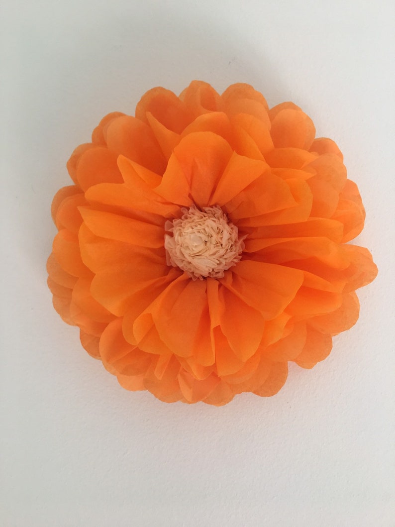 Puede incluir: Una gran flor de papel naranja con m&uacute;ltiples capas de p&eacute;talos y un centro beige claro. La flor es redonda y parece estar hecha de papel fino y transl&uacute;cido. Los p&eacute;talos son de color naranja vibrante.