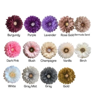 May include: A collection of artificial flowers in various colors, including burgundy, purple, and lavender. Each flower has a central disc and is labeled with its color name: Burgundy, Purple, Lavender, Rose Gold Bermuda Sand, Dark Pink, Blush, Champagne, Vanilla, Birch, White, Gray Mist, Gray, and Gold.
