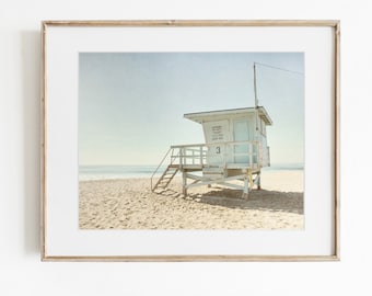 Könnte beinhalten: Ein gerahmter Kunstdruck, der einen weißen hölzernen Rettungsschwimmerturm mit der Nummer 3 zeigt, der auf einem Sandstrand unter klarem Himmel steht. Das Bauwerk verfügt über eine Treppe und eine kleine Tür vor einem ruhigen Meereshorizont.