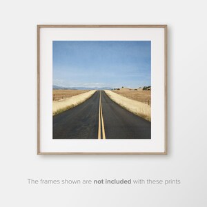 May include: A long, straight, paved road with yellow lines down the centre, leading to a distant horizon. The road is surrounded by dry, golden grass and a blue sky.