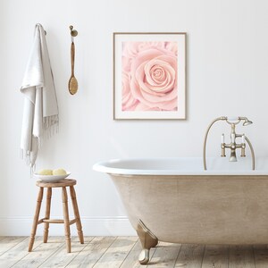 May include: A white bathtub with gold-toned faucet fixtures and a single, pale pink rose in a framed print above the tub.