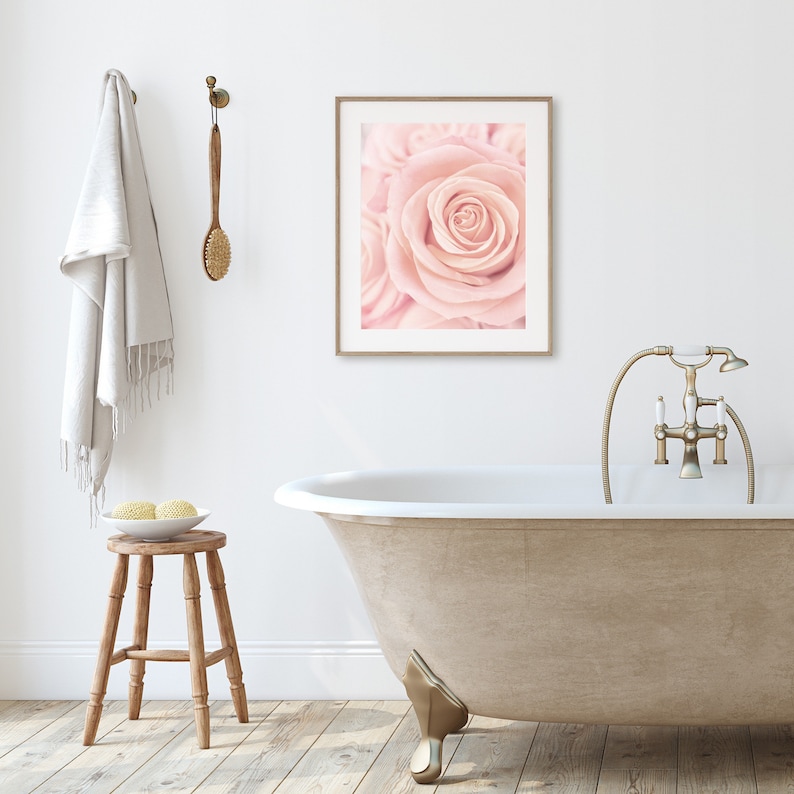 May include: A white bathtub with gold-toned faucet fixtures and a single, pale pink rose in a framed print above the tub.