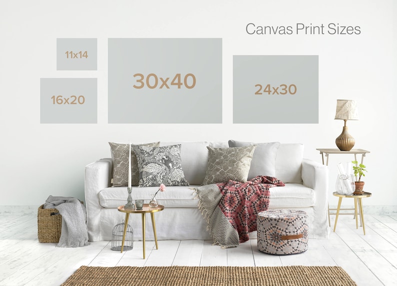 May include: A white couch with pillows and a throw blanket in a living room setting. The wall behind the couch has a sign that reads "Canvas Print Sizes" with four different sizes listed: 11x14, 16x20, 30x40, and 24x30.