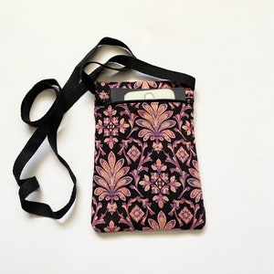 May include: A black crossbody bag with a pink and purple floral pattern. The bag has a zipper closure and a long adjustable strap.