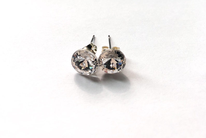 Peut inclure: Une paire de boucles d'oreilles clous en argent avec des pierres rondes en cristal transparent.