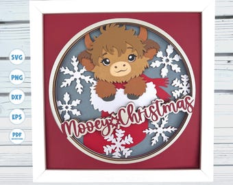 May include: A framed, layered paper art piece featuring a cartoon Highland cow peeking out of a Christmas stocking. The artwork includes snowflakes and the text "Moovey Christmas" in a festive design. The background is red and gray.