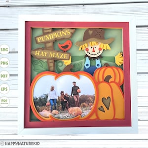 May include: A white frame with a red mount surrounding a picture with a fall theme. The picture features a scarecrow with a sign that reads "Pumpkins Hay Maze". A family is pictured in a pumpkin cutout.