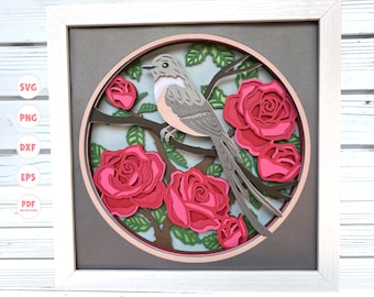 Puede incluir: Un diseño de papel con un pájaro gris posado en una rama con rosas rosas. El diseño está enmarcado en un marco blanco con un passe-partout gris.