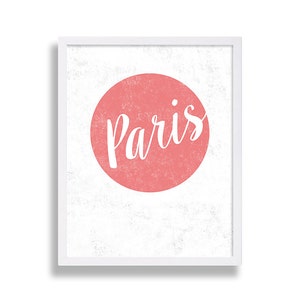 May include: A white framed print with a pink circle and the word "Paris" in white cursive lettering.