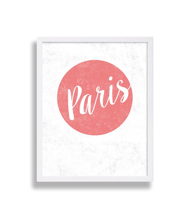 May include: A white framed print with a pink circle and the word "Paris" in white cursive lettering.