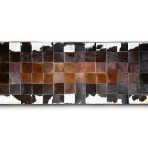 May include: A rectangular cowhide rug with a patchwork design. The rug is made up of squares of different colors of brown, black, and white cowhide. The rug is perfect for adding a touch of rustic charm to any room.