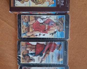 May include: A set of tarot cards with black borders and colorful illustrations. The box is brown with gold lettering that reads "TAROCCHI ILLUMINATI". The cards show the numbers 0, XVI, and VIII.