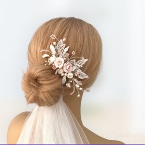 K&ouml;nnte beinhalten: Ein rosafarbener und goldener Blumenhaarkamm mit Perlenakzenten. Der Kamm ist mit zarten Bl&auml;ttern und Bl&uuml;ten verziert, perfekt f&uuml;r eine Hochzeit oder einen besonderen Anlass.