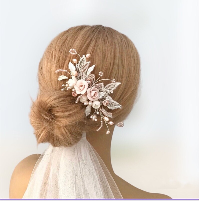 K&ouml;nnte beinhalten: Ein rosafarbener und goldener Blumenhaarkamm mit Perlenakzenten. Der Kamm ist mit zarten Bl&auml;ttern und Bl&uuml;ten verziert, perfekt f&uuml;r eine Hochzeit oder einen besonderen Anlass.