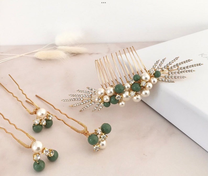 K&ouml;nnte beinhalten: Ein Set aus drei goldenen Haark&auml;mmen mit gr&uuml;nen und wei&szlig;en Perlenakzenten. Die K&auml;mme sind mit Strasssteinen verziert und haben ein zartes, feminines Design.