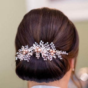 Rose gold coloured hair vine featuring pearls ,crystals and leaves which is wing worn by a bride with dark hair