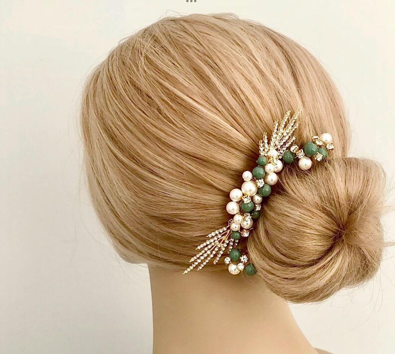 K&ouml;nnte beinhalten: Goldener Haarkamm mit gr&uuml;nen und wei&szlig;en Perlen. Der Kamm hat ein zartes, blattf&ouml;rmiges Design und ist perfekt, um jeder Frisur einen Hauch von Eleganz zu verleihen.