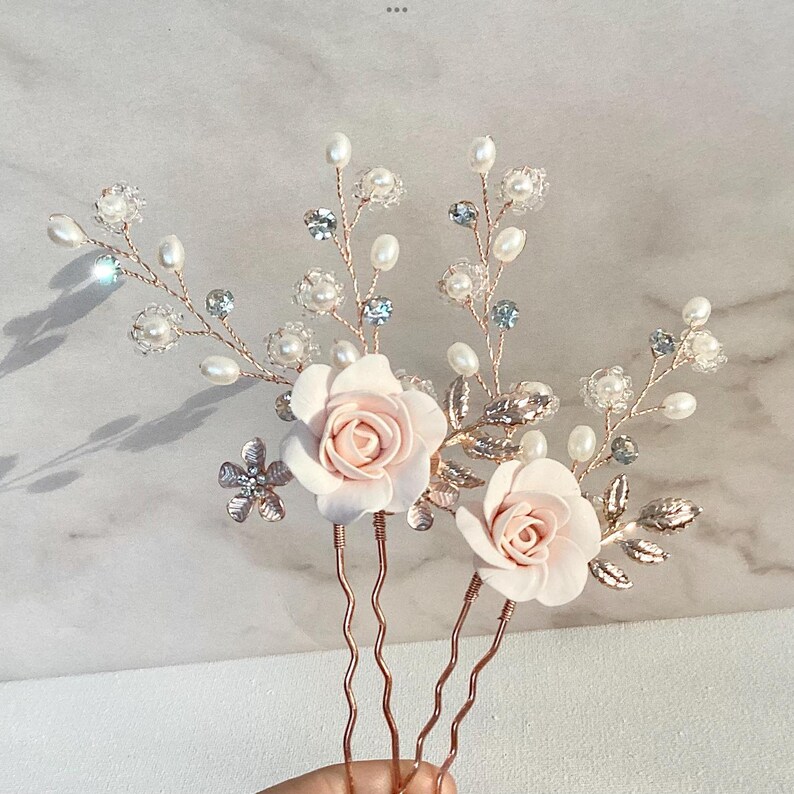 May include: Three gold hair pins with pink fabric roses and pearl and crystal embellishments.