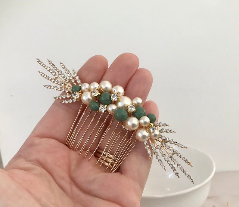 K&ouml;nnte beinhalten: Goldener Haarkamm mit einem Cluster aus Kunstperlen und gr&uuml;nen Perlen. Der Kamm hat ein dekoratives Design mit Strasssteinen.
