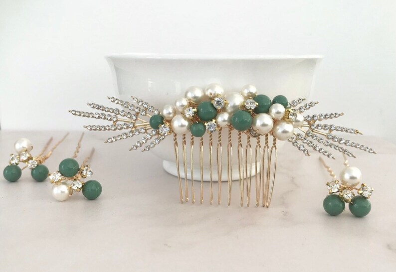 K&ouml;nnte beinhalten: Ein goldener Haarkamm mit einem Cluster aus Kunstperlen und gr&uuml;nen Perlen sowie zwei kleinere Haarnadeln mit Kunstperlen und gr&uuml;nen Perlen.
