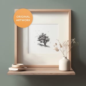 May include: A framed black and white pencil drawing of a tree with birds flying around it. The frame is light wood and is sitting on a shelf with a small wooden bowl and a white vase with dried flowers.