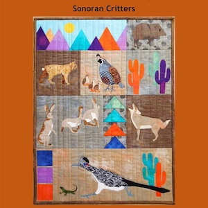 May include: A handmade quilt featuring Sonoran Critters. The quilt showcases various desert animals like a bobcat, quail, rabbits, coyote, and roadrunner, along with cacti and mountains. The design includes the text "Trouble & Boo Designs" and "Sonoran Critters".