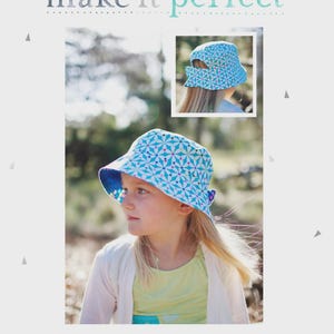 May include: A blue and white patterned sun hat with a wide brim, worn by a young person. The hat has a floral design and a contrasting blue interior. The image also includes the text "SUN KISSED HAT" and "make it perfect".