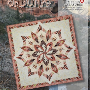 May include: A square quilt pattern titled Sedona by Timeless Treasures featuring a central star design with geometric diamond shapes in shades of rust, brown, cream, and tan, surrounded by a cream border with swirling quilted textures.